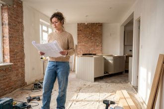 Femme en rénovation tenant des plans architecturaux